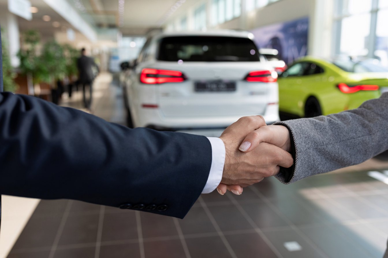 Buyer and Seller at Car Dealership Shaking Hands after Buying a Car
